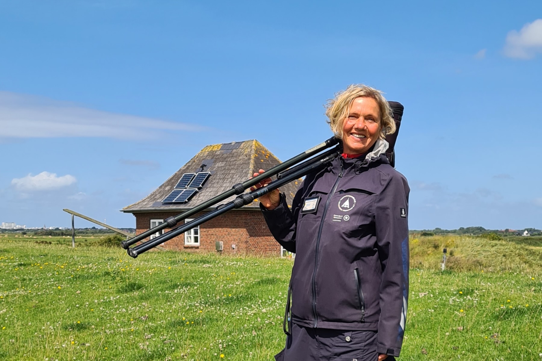 Vogelwartin mit Fernrohr am Deich Vogelwartin mit Fernrohr am Deich